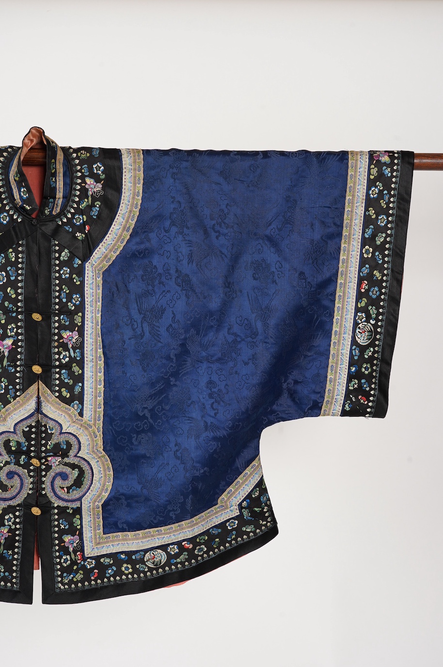 A late 19th century Chinese blue silk damask jacket, woven with Phoenix and auspicious symbols. The jacket edged with ornate rows of braiding and silk embroidery, the interior with original pink silk lining. The jacket f